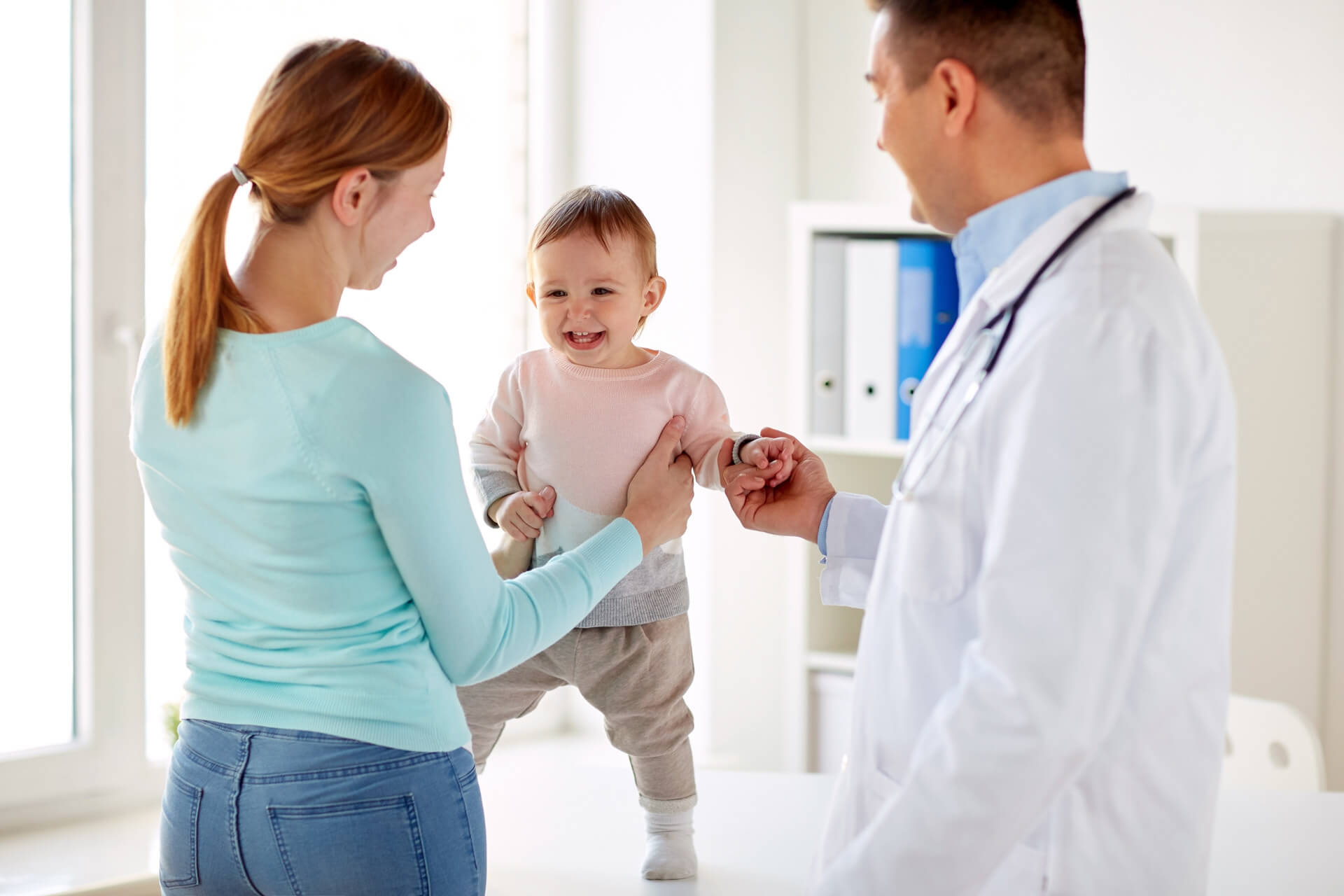 happy woman with baby and doctor at clinic